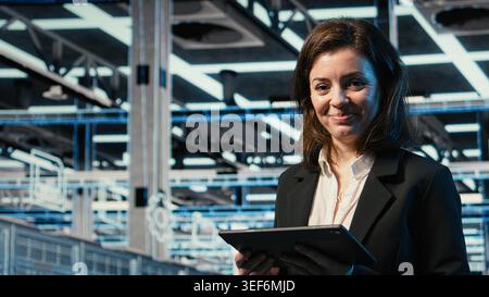 Close up of data center DevOps engineer optimizing server load balancing using tablet. Server farm worker adjusting system parameters on device to improve efficiency Stock Photo