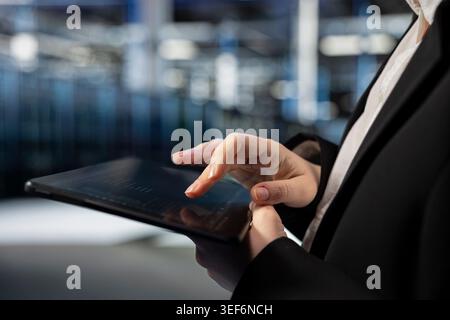 Close up of data center computer scientist typing on tablet, configuring gear hosting digital services. Server farm employee writing code with touchscreen device to repair infrastructure Stock Photo