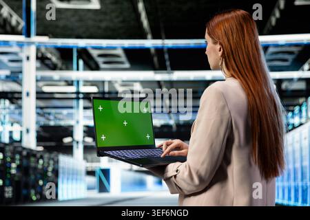 Isolated screen laptop used by data center system administrator to manage database storage. Server farm worker uses chroma key notebook to monitor cloud computing hardware, technology concept Stock Photo