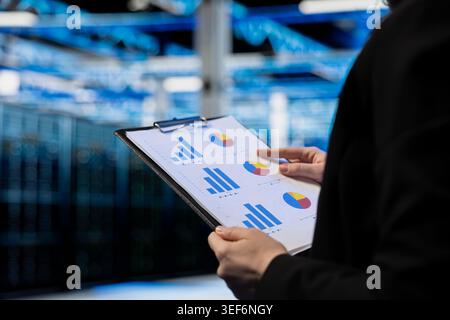 Close up of data center admin auditing documentation, checking equipment, doing system management. Server farm manager checks technical files for accuracy, planning disaster recovery protocols Stock Photo