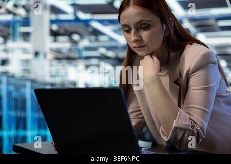 Close up of data center admin using laptop to manage database storage rigs. Server hub employee worker uses notebook to monitor internet cloud computing equipment, technology concept Stock Photo