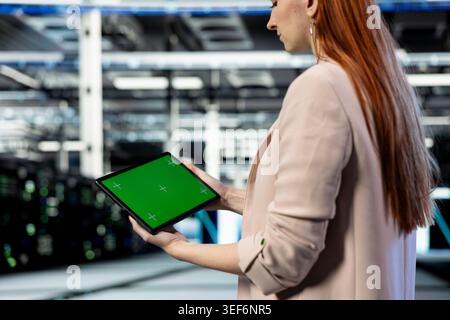 Green screen tablet used by data center manager deploying protection against network threats. Server farm cybersecurity department worker audits systems for computer bugs with chroma key device Stock Photo