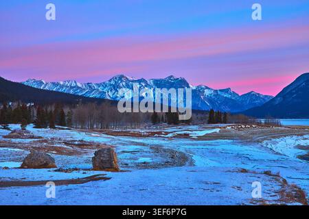 Snowy Sunrise Landscape with Majestic Mountain Range and Pine Trees in Winter Stock Photo