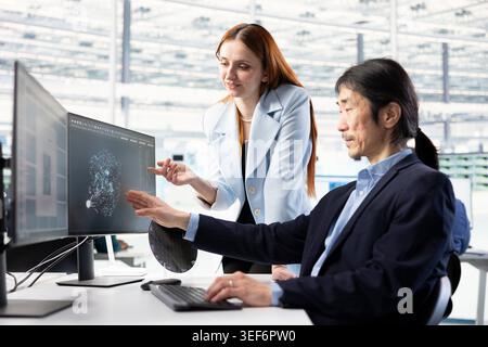 Examining microchip circuit design, AI and female technician with coworker. Supervising semiconductors, artificial intelligence and Asian man with colleague in automated manufacturing plant Stock Photo