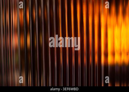 Golden amber glowing light lines passing through corrugated glass pattern Stock Photo