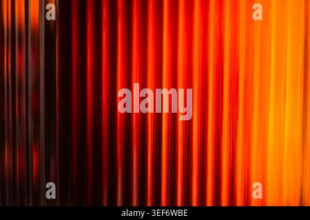 Intense red and orange warm light gradient behind striped glass Stock Photo