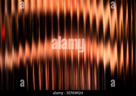 Warm copper and orange vertical blurred streaks creating a metallic abstract texture Stock Photo