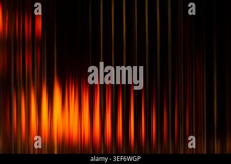 Intense fiery orange and yellow vertical blurred flares against a pitch black background Stock Photo