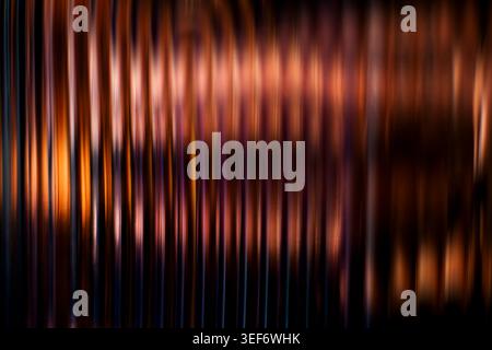 Dark copper and orange abstract vertical blurred lines creating a warm metallic ribbed texture Stock Photo