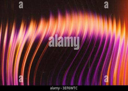 Vibrant purple and orange curved light streaks creating a dynamic abstract background with film texture Stock Photo