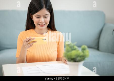 woman use phone scan barcode or QR codes to pay credit card bill after receiving document invoice. payment, receive, paying electricity, digital payme Stock Photo