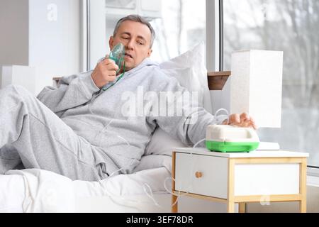 Mature man using nebulizer in bedroom Stock Photo
