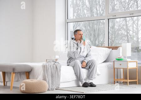 Mature man using nebulizer in bedroom Stock Photo