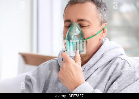 Mature man using nebulizer in bedroom, closeup Stock Photo
