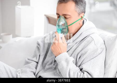 Mature man using nebulizer in bedroom Stock Photo