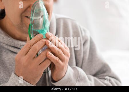Mature man using nebulizer in bedroom, closeup Stock Photo
