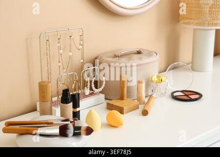 Cosmetic bag, different makeup brushes and decorative cosmetics on table in room, closeup Stock Photo