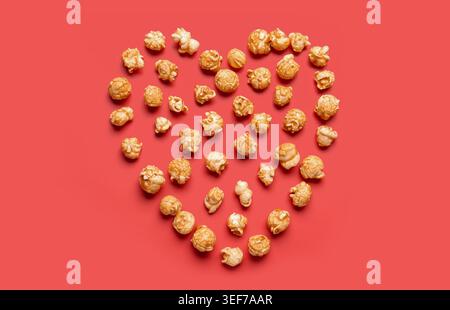 Heart made of crispy popcorn on red background Stock Photo