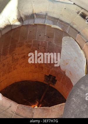Authentic documentary detail of traditional flatbread baking inside a heated circular brick and clay oven. The dough is stuck directly to the hot maso Stock Photo