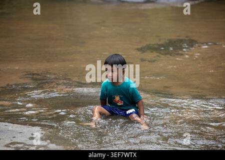 CHIANG MAI, THAILAND-APR 16, 2026: Boy during outdoor water activity in freshwater stream, front view, Mae Ya Waterfall. Stock Photo