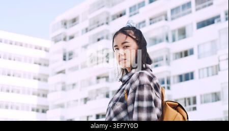 City, portrait and asian woman on campus for education, travel and outdoor in urban town. Confident, serious and student or female person in backpack Stock Photo