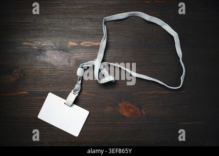 Blank badge with lanyard on wooden background. Blank plastic id card. White plastic badge. Flat lay Stock Photo