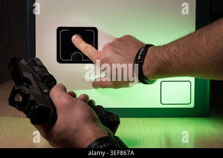 Man using biometric fingerprint scanner to open a modern home safe for secure handgun storage. Stock Photo