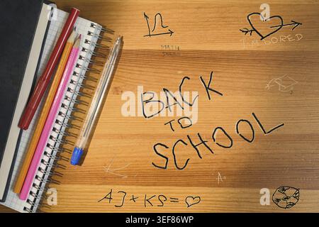 Back to school writing on wooden desk. Top view of school table with supplies and accessories. Shadow and sun beam overlay Stock Photo
