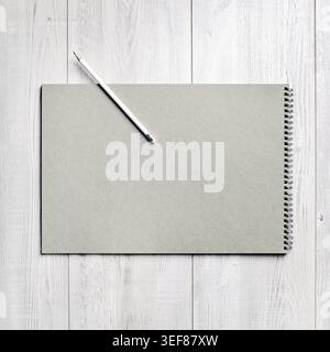 Blank notebook and pencil on light wooden surface. Branding template. Flat lay Stock Photo