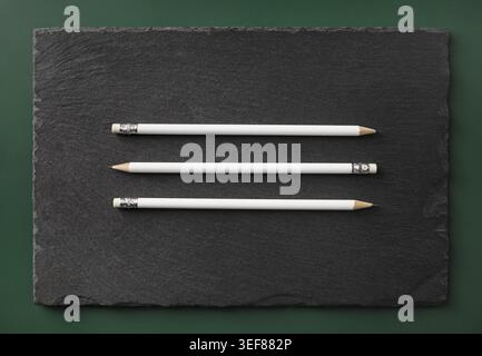 Three blank white pencils with copy space on stone board. Template for branding identity. Flat lay Stock Photo