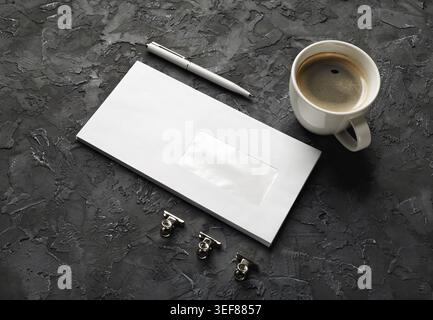 Photo of blank envelope, pen and coffee cup on black plaster background. Template for branding identity Stock Photo