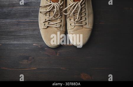 Sand-colored boots on brown wooden background. Flat lay Stock Photo