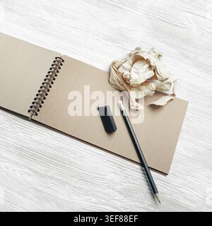 Photo of kraft notepad, pencil, eraser and crumpled paper on light wood table background Stock Photo