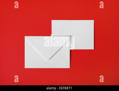 Two blank paper envelopes on red paper background. Back and front. Top view. Flat lay Stock Photo