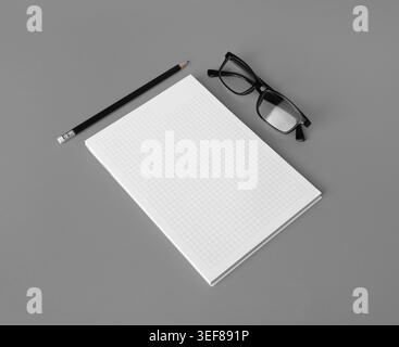Photo of blank copybook, glasses and pencil on gray paper background. Copy space for text Stock Photo