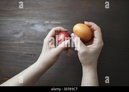 Easter eggs in female hands on wooden background Stock Photo