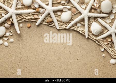 White starfishes, stones and seashells on sand background with fishing net. View from above. Flat lay Stock Photo