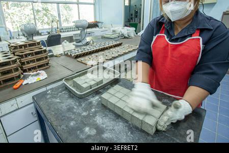 An Asian woman in a face mask and gloves works at a mining factory. Stock Photo