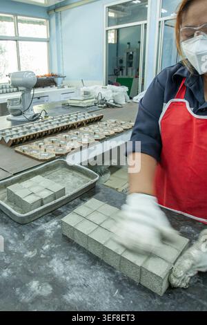 An Asian woman in a face mask and gloves works at a mining factory. Stock Photo