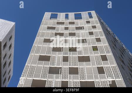 View of the blue sky of the white facade of a modern residential building with ornamental grid structures and square window openings in the Port Mari Stock Photo