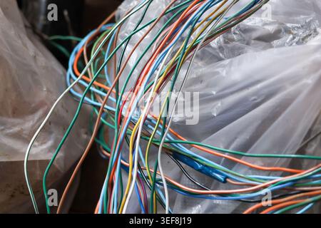 Tangled bundle of colorful electrical wire and cable resting on clear plastic wrap representing chaotic frustrating technology connection and complex Stock Photo