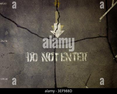 Damaged pavement features spray-painted warning text Stock Photo