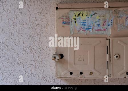 Vintage metal mailboxes mounted on textured wall in old apartment building corridor. Urban residential detail with worn surfaces and retro aesthetic Stock Photo