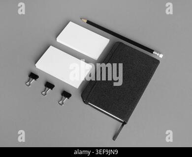 Photo of black notebook, blank business cards and pencil on gray paper background Stock Photo