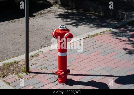 Red fire hydrant on paved footway in Bucharest, Romania Stock Photo