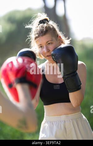 Woman training boxing with punch mitts outdoors Stock Photo