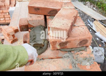 Professional construction worker laying bricks on house construction site. Stock Photo