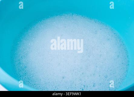 Hand laundry washing clothes in blue plastic basin, soaked white cloth handwash, housework Stock Photo