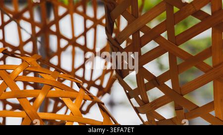 Interlocking strips of golden-amber bamboo weave together in a complex geometric pattern, photographed in close-up in Kyoto to reveal the intricate hand-craftsmanship of traditional Asian basketry. Ideal as a warm textured background or pattern reference. Stock Photo