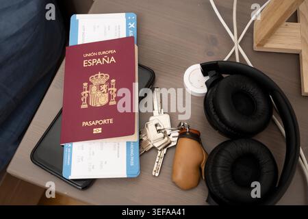 Spain passport, boarding pass, keys, smartphone and headphones on a bedside table Stock Photo